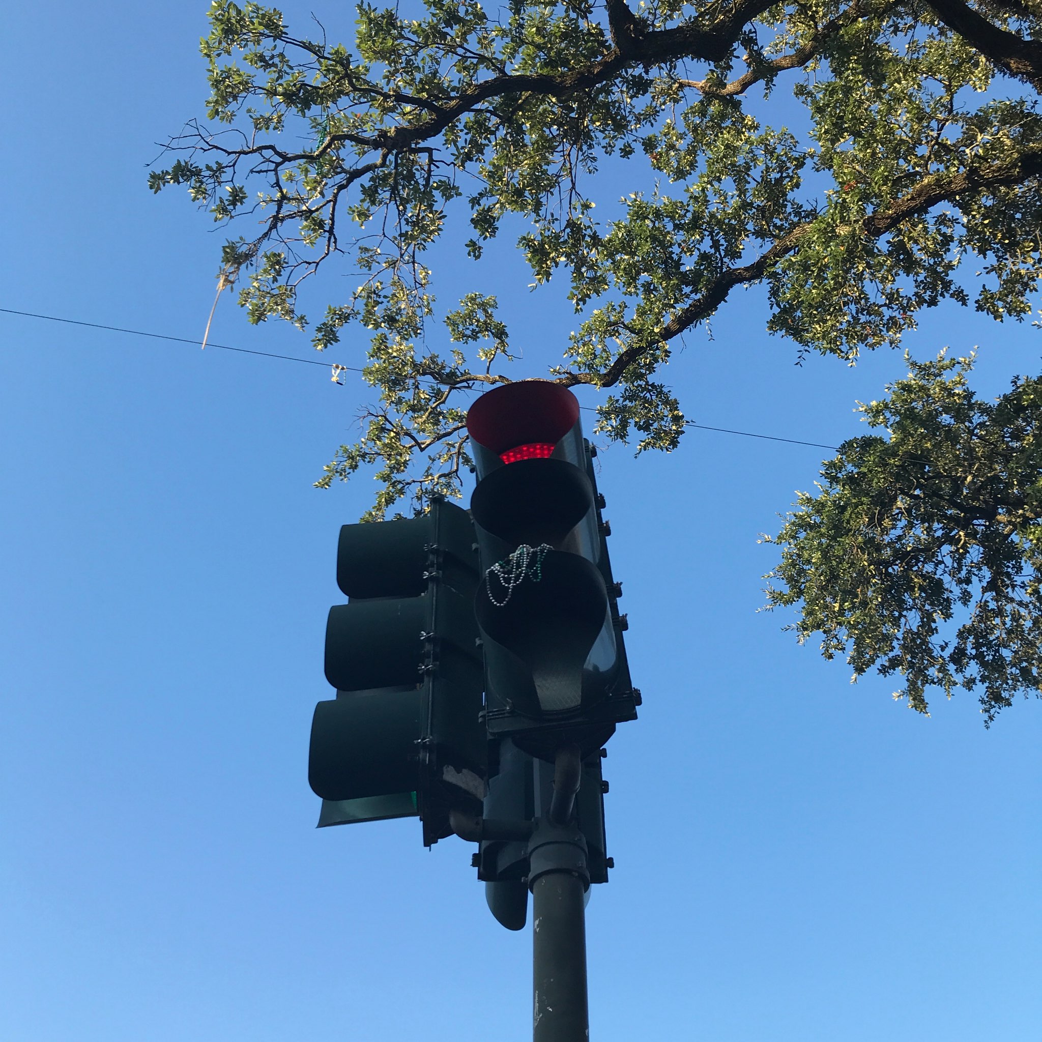 Red traffic light adorned in Mardi Gras throws